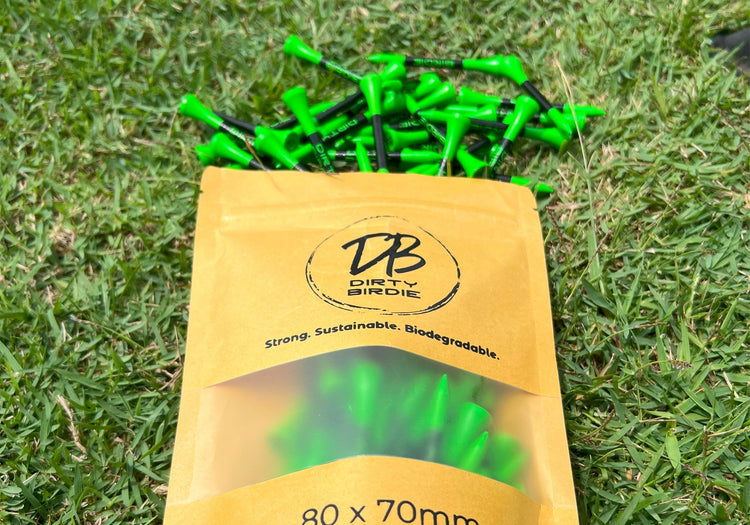 Dirty Birdie bamboo golf tees spilling from custom bag onto the green – durable, branded, and built for performance