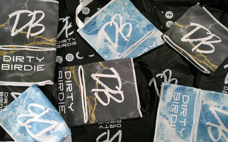 Golf towels stacked on custom Dirty Birdie packaging – premium designs, bold colours, and functional detailing on display