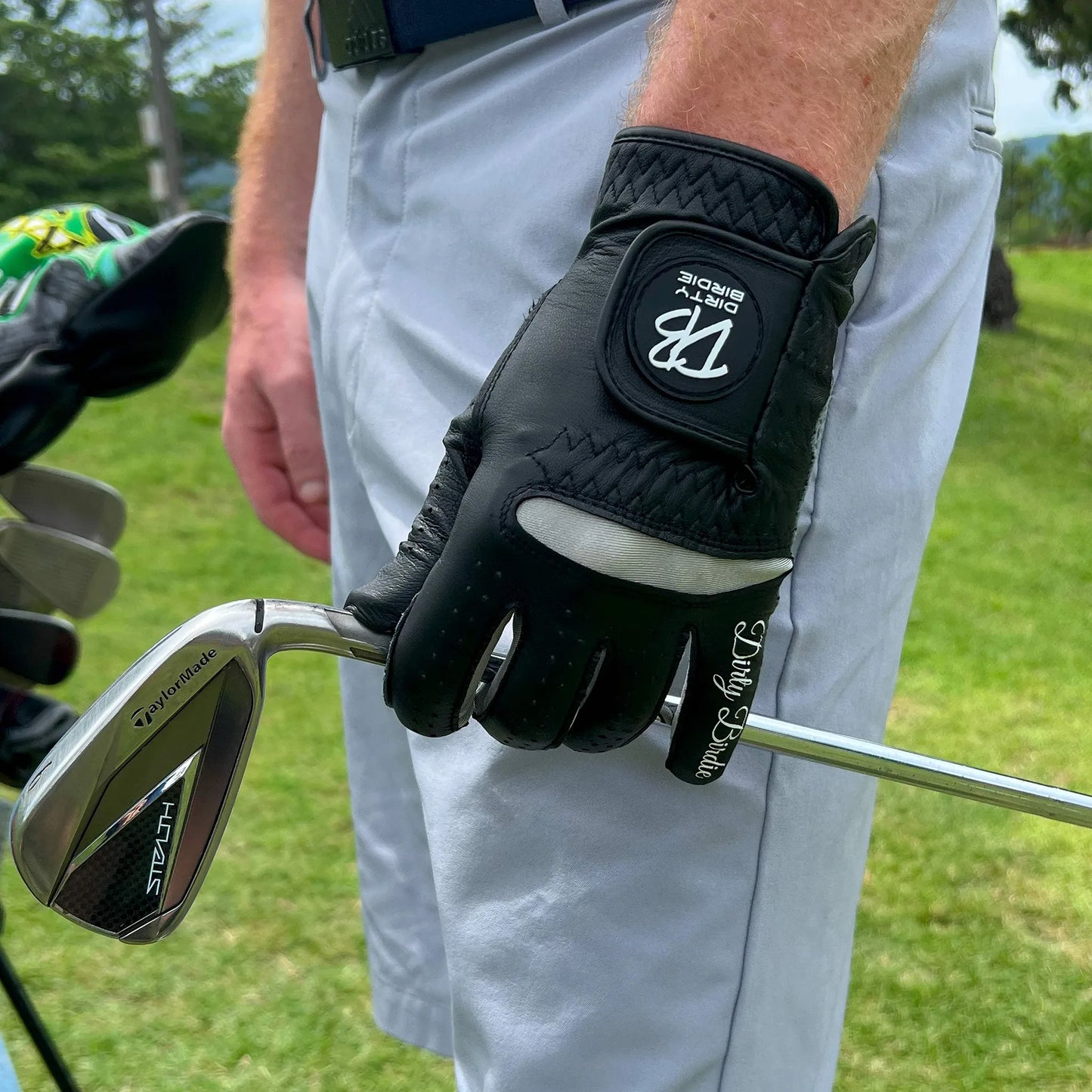 Black Premium golf glove holding iron shaft after a shot on course