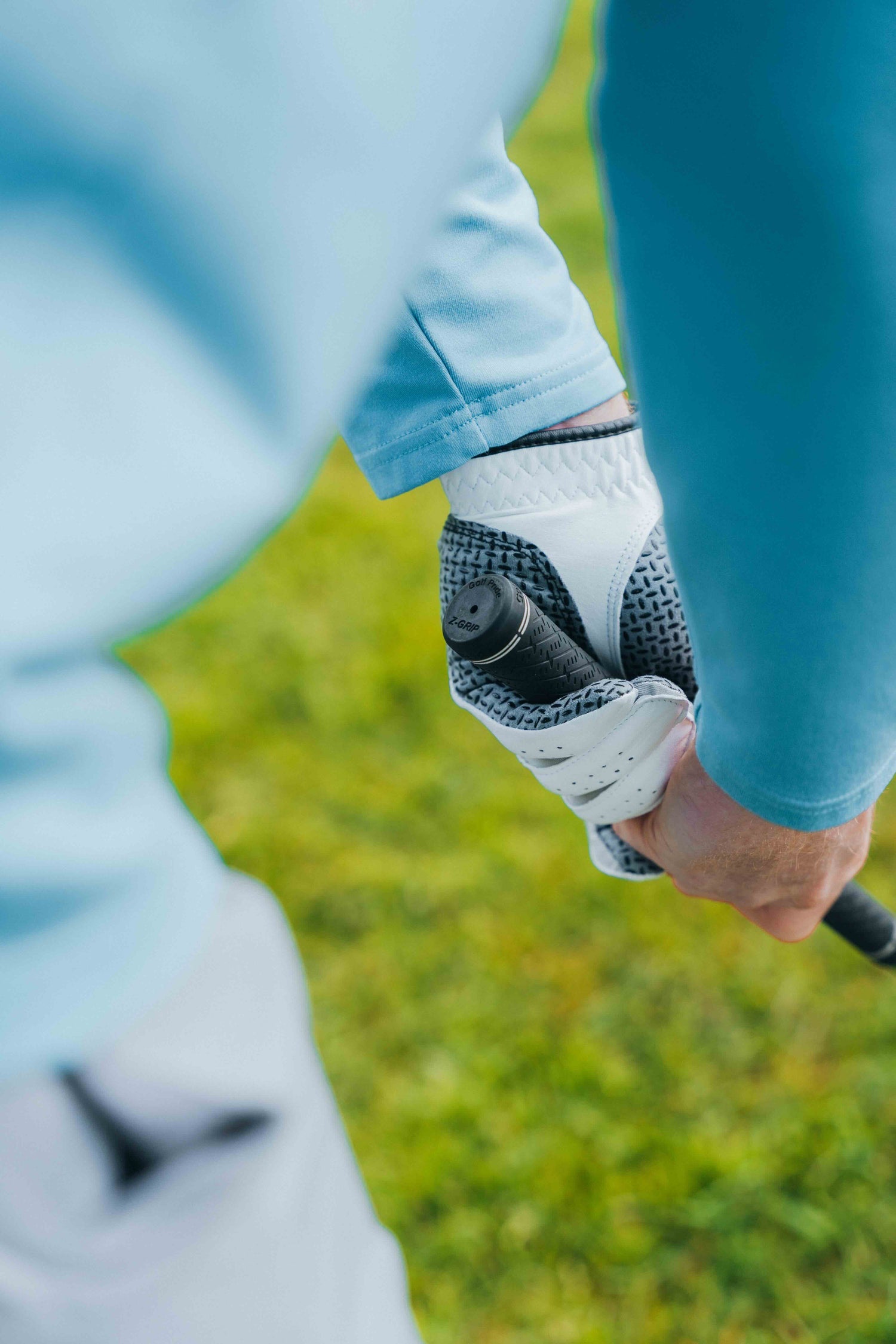Premium golf glove with enhanced grip holding golf club on course from behind hands