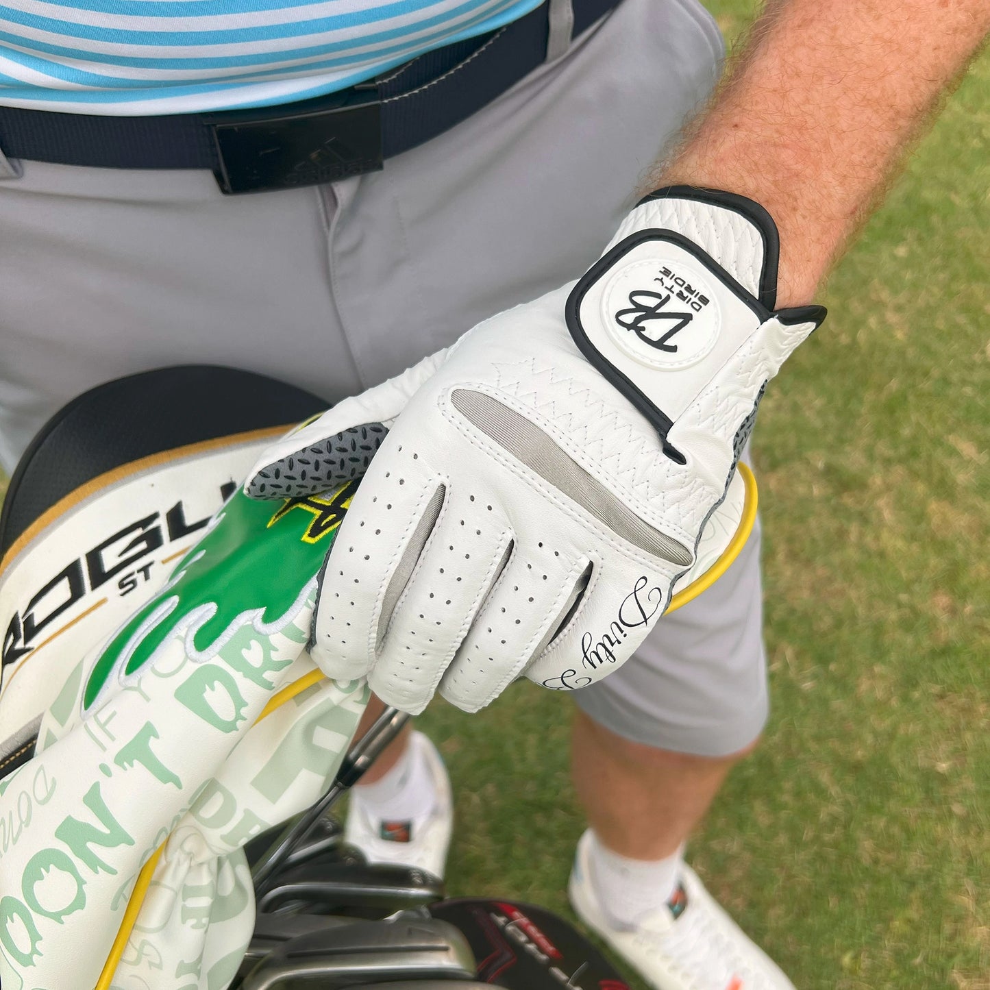 Classic white golf glove made from soft premium leather holding driver head on course