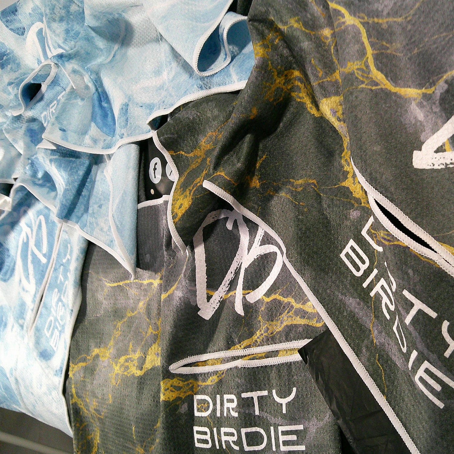 Black and blue golf towels arranged in a textured, layered display showcasing premium waffle knit and subtle detailing.