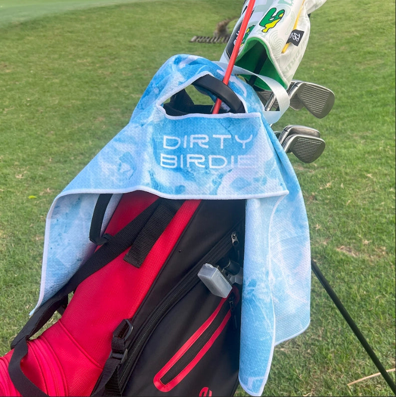 Blue Ice waffle golf towel hanging via centre hole from golf bag, on-course with visible design and rich knit detail.
