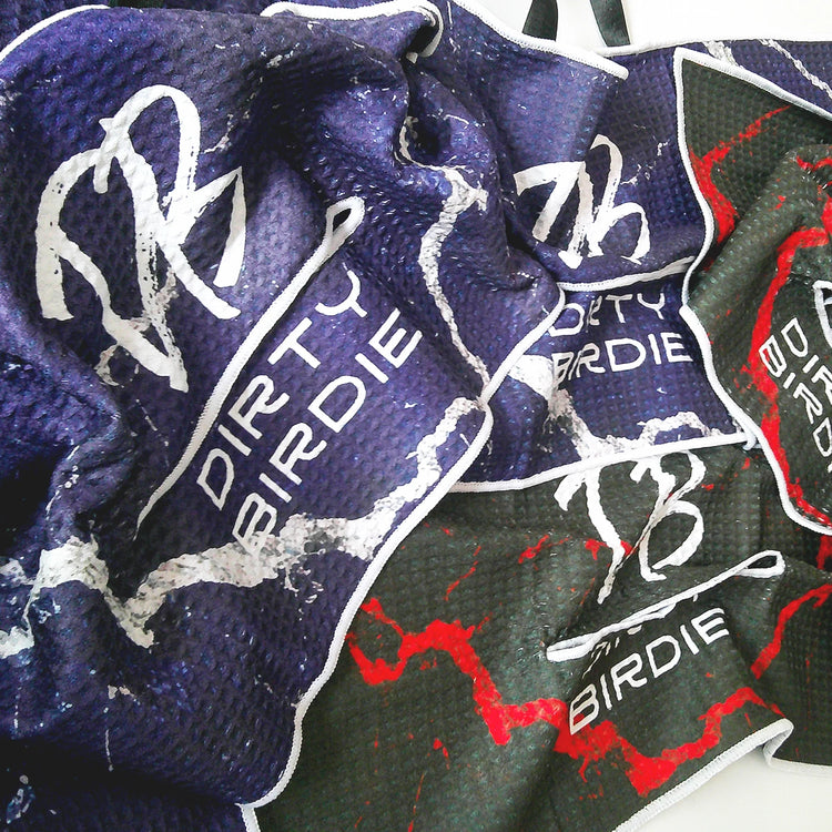 Golf towels stacked on custom Dirty Birdie packaging – premium designs, bold colours, and functional detailing on display