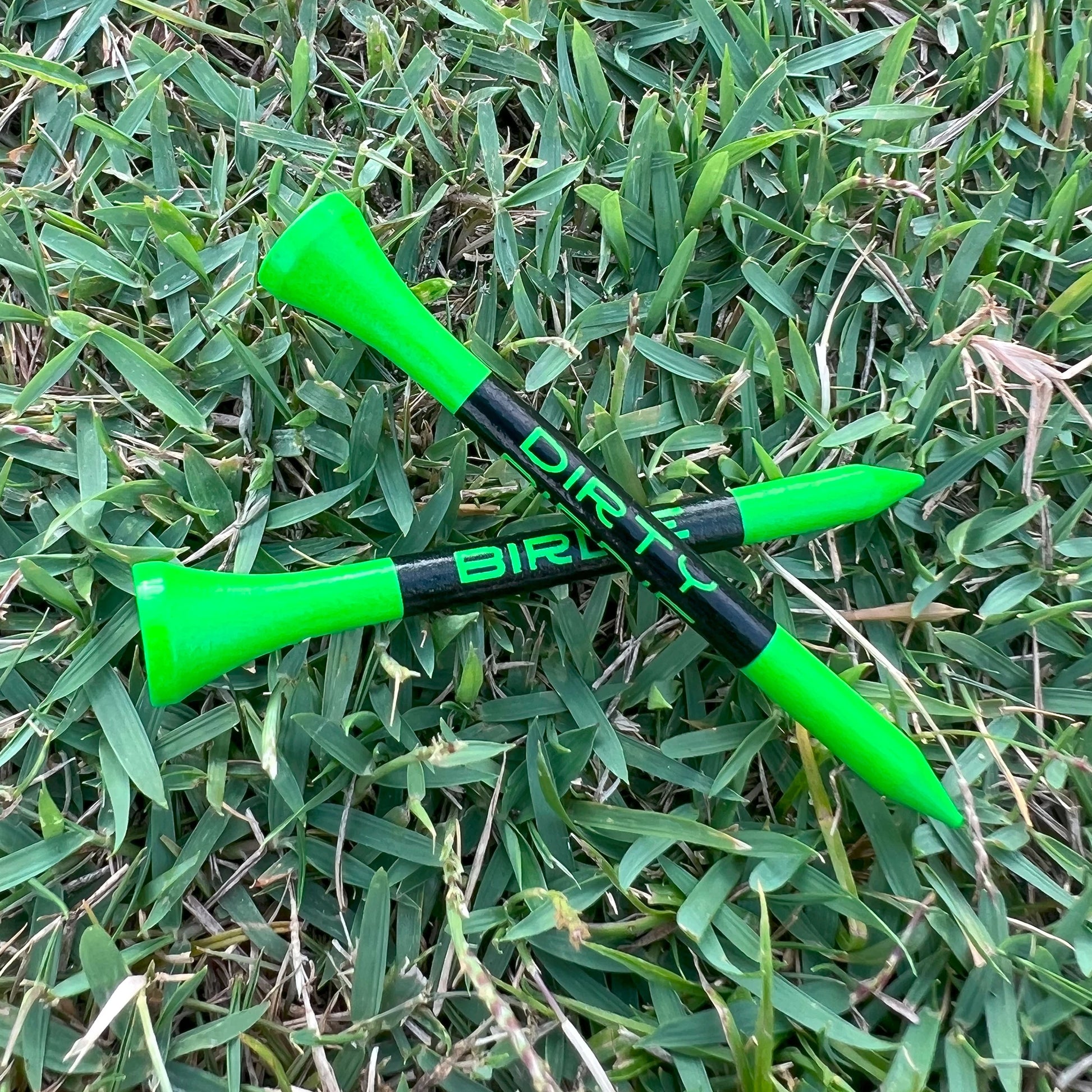 Two golf tees on laying on top of each other positioned on the tee box showing Dirty Birdie name on Shaft