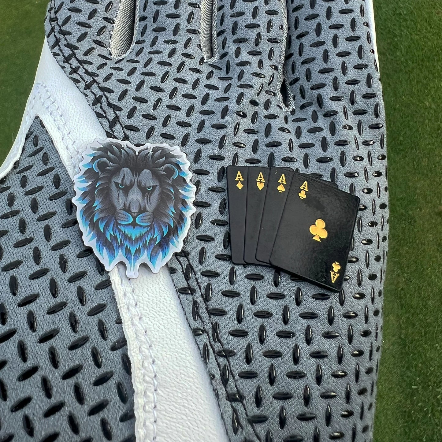 Detailed golf ball markers held in gloved hand showing size and finish 